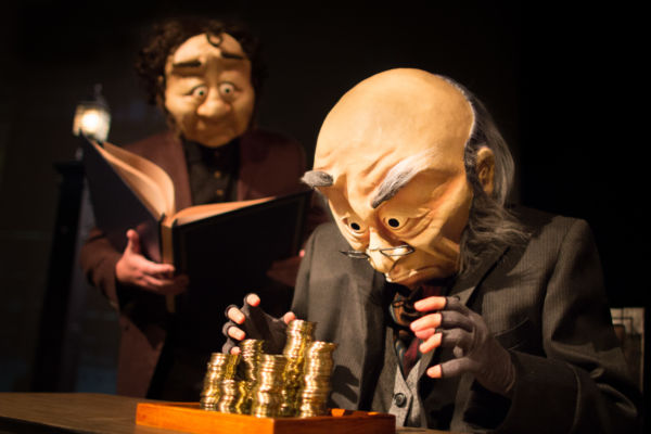 Ebenezer Scrooge looms over a stack of gold coins while Bob Cratchit calculates the day's earnings. ‘A WONDERHEADS Christmas Carol’ is a whimsical reimagining of the holiday classic, touring BC theatres this December. Kate Braidwood as Scrooge and Andrew Phoenix as Bob Cratchit. Photo by Daryl Turner (Dimensions: 4000 x 2667px • File Type: JPG • File Size: 3MB) Ebeneezer Scrooge ogles a stack of gold coins with Bob Cratchit looking on in the background. From 'A WONDERHEADS Christmas Carol' by WONDERHEADS, a physical theatre company specializing in full-face mask performance.